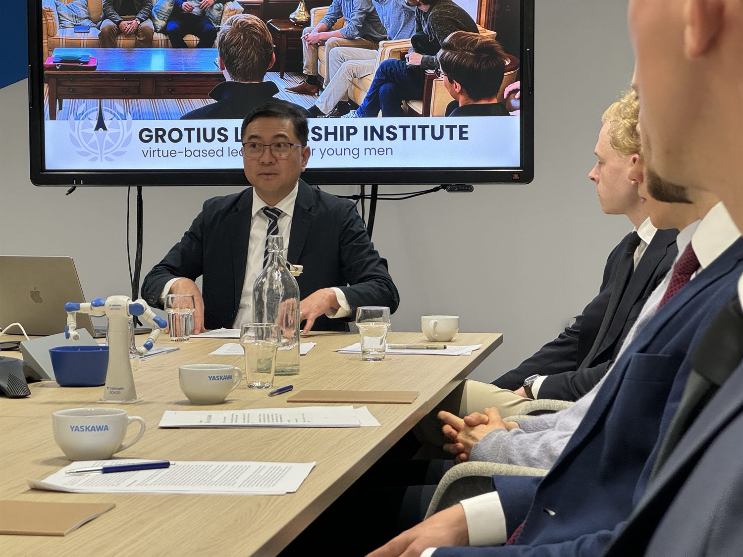 A course session held inside a company, with the Grotius Leadership Institute slide on screen